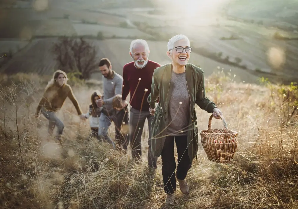 En familie som går smilende gjennom en solfylt eng.