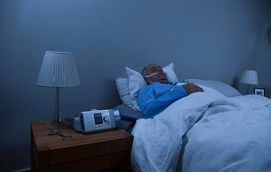En mannlig KOLS-pasient som sover i sengen hjemme mens han mottar HFT