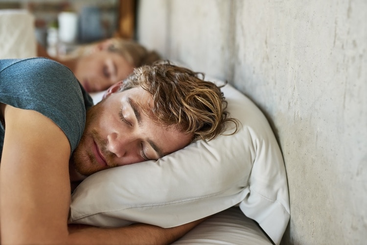 Mann som sover på siden, med pute