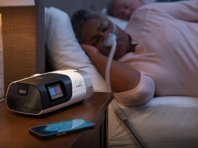 ResMed-søvnapné-pasient-sove-nesemaske-CPAP-apparat-400x300
