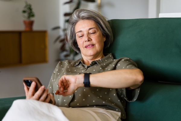 Kvinne som ser på Apple Watch og telefonen sin