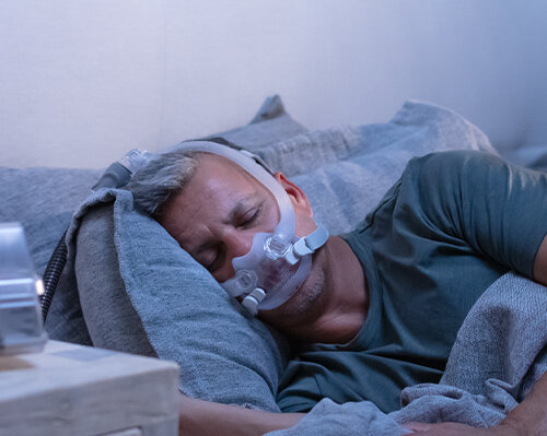 pasient-sove-med-AirFit-F30i-rør-up-CPAP-maske-mobile Resmed-Norge